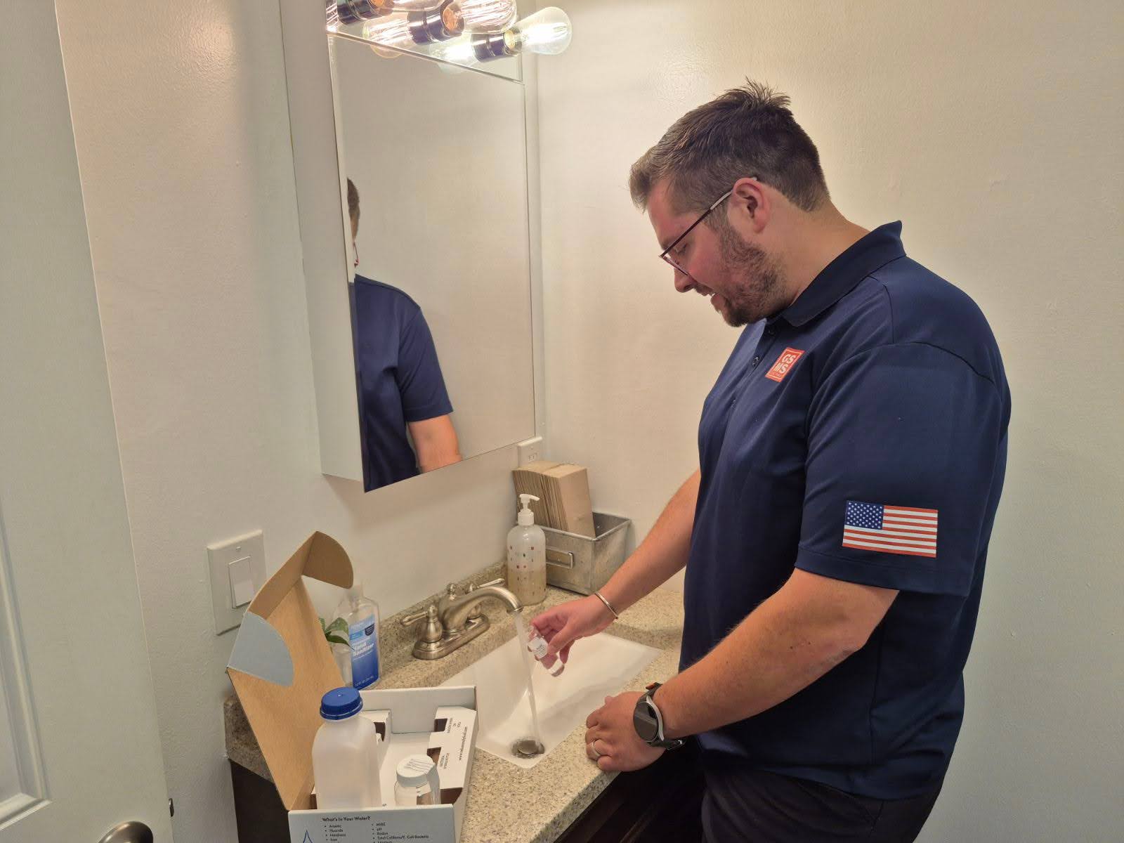 Technician collecting water sample from bathroom sink for a water quality test